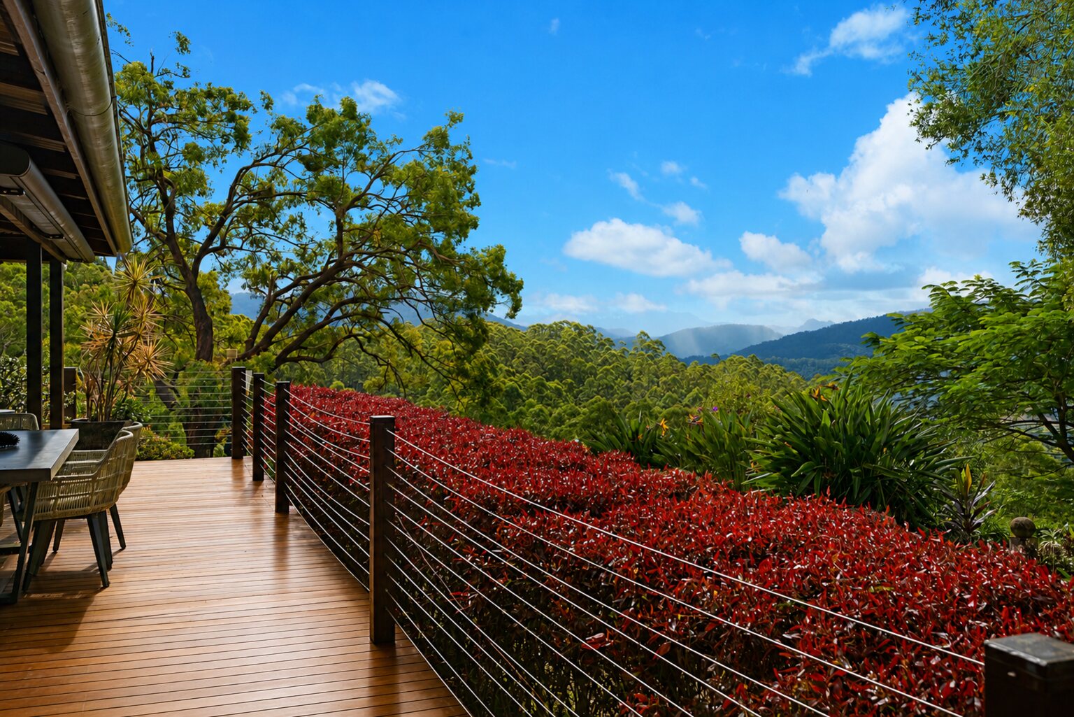 Timber deck and dining terrace with a red-foliage hedge, overlooking the caldera ranges at Serra Luma